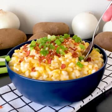 Cheesy corn in blue bowl with toppings. 