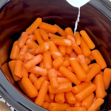 Melted butter bring added to baby carrots.