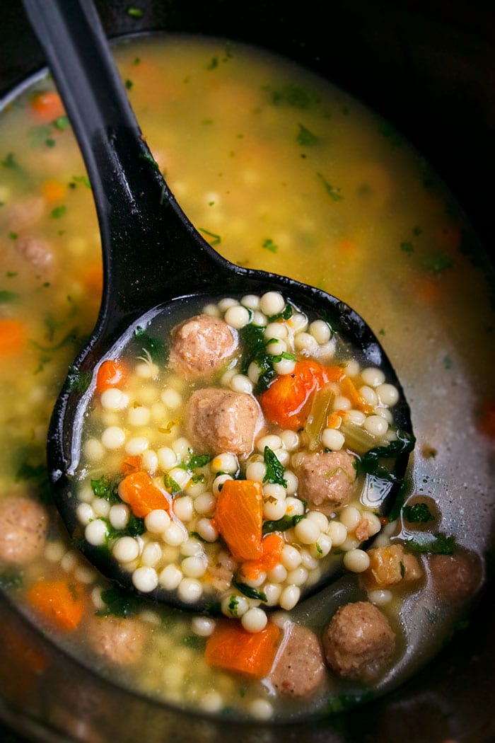 Easy Italian Wedding Soup in Black Slow Cooker with Black Spoon