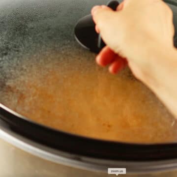 Lid being placed on top of the slow cooker to cover it. 
