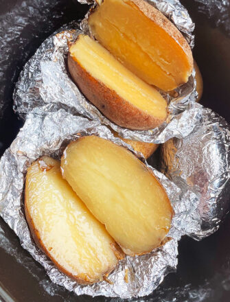 Baked Potatoes Wrapped in Foil in Black Slow Cooker