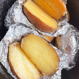 Baked Potatoes Wrapped in Foil in Black Slow Cooker