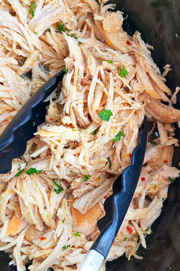 Easy Juicy Homemade Pulled Chicken in Black Slow Cooker With Tongs 