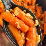 Spoonful of Easy Candied Carrots With Honey and Orange Juice over Black Slow Cooker