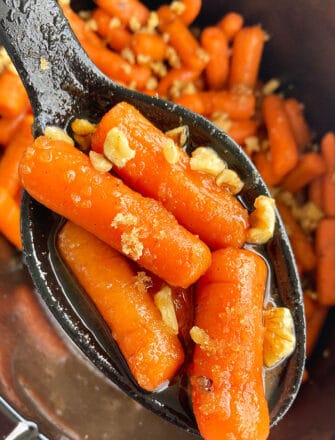 Spoonful of Easy Candied Carrots With Honey and Orange Juice over Black Slow Cooker