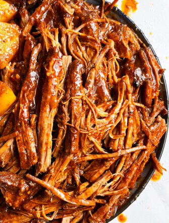Slow Cooker Shredded Beef With BBQ Sauce Served in White Plate With Black Rims- Overhead Shot