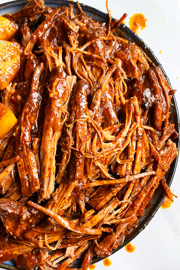Slow Cooker Shredded Beef With BBQ Sauce Served in White Plate With Black Rims- Overhead Shot