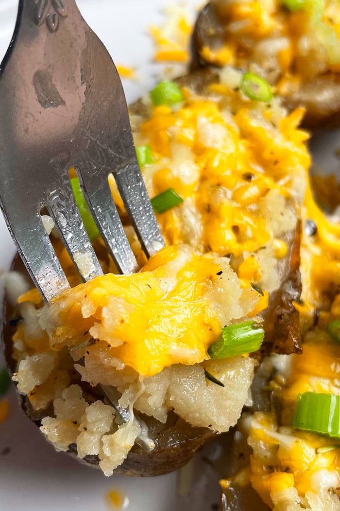 Fork Full of Cheesy Potato Skins in White Plate- Closeup Shot