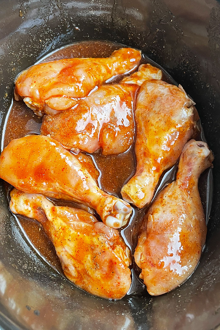 Raw Chicken Drumsticks in Asian Sauce in Black Slow Cooker- Overhead Shot