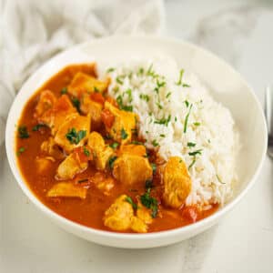 Easy Slow Cooker Paprika Chicken (Paprikash) Served in White Bowl With Rice.