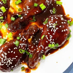 White Dish Full of Sticky Korean Chicken Drumsticks.