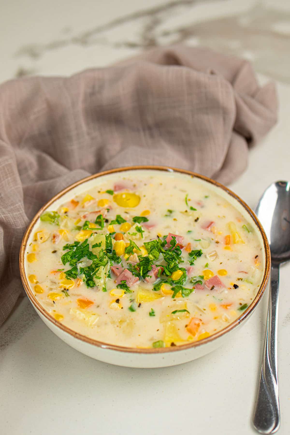 Bowl of Best Slow Cooker Corn Chowder on White Marble Background. 