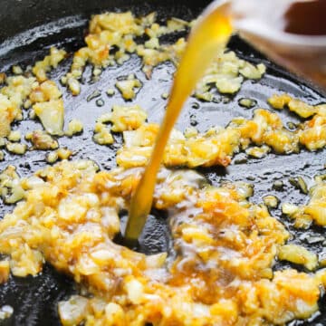 Broth and gravy mixture being added to sautted onions in pan. 