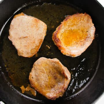 Seared steaks in black nonstick pan. 