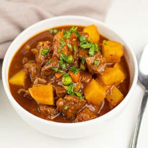 White bowl filled with the best easy slow cooker beef bourguignon on white background.