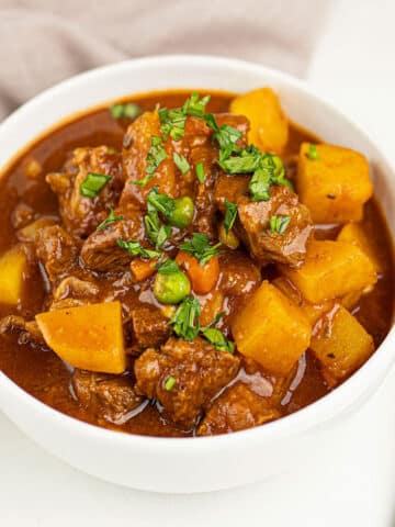 White bowl filled with the best easy slow cooker beef bourguignon on white background.