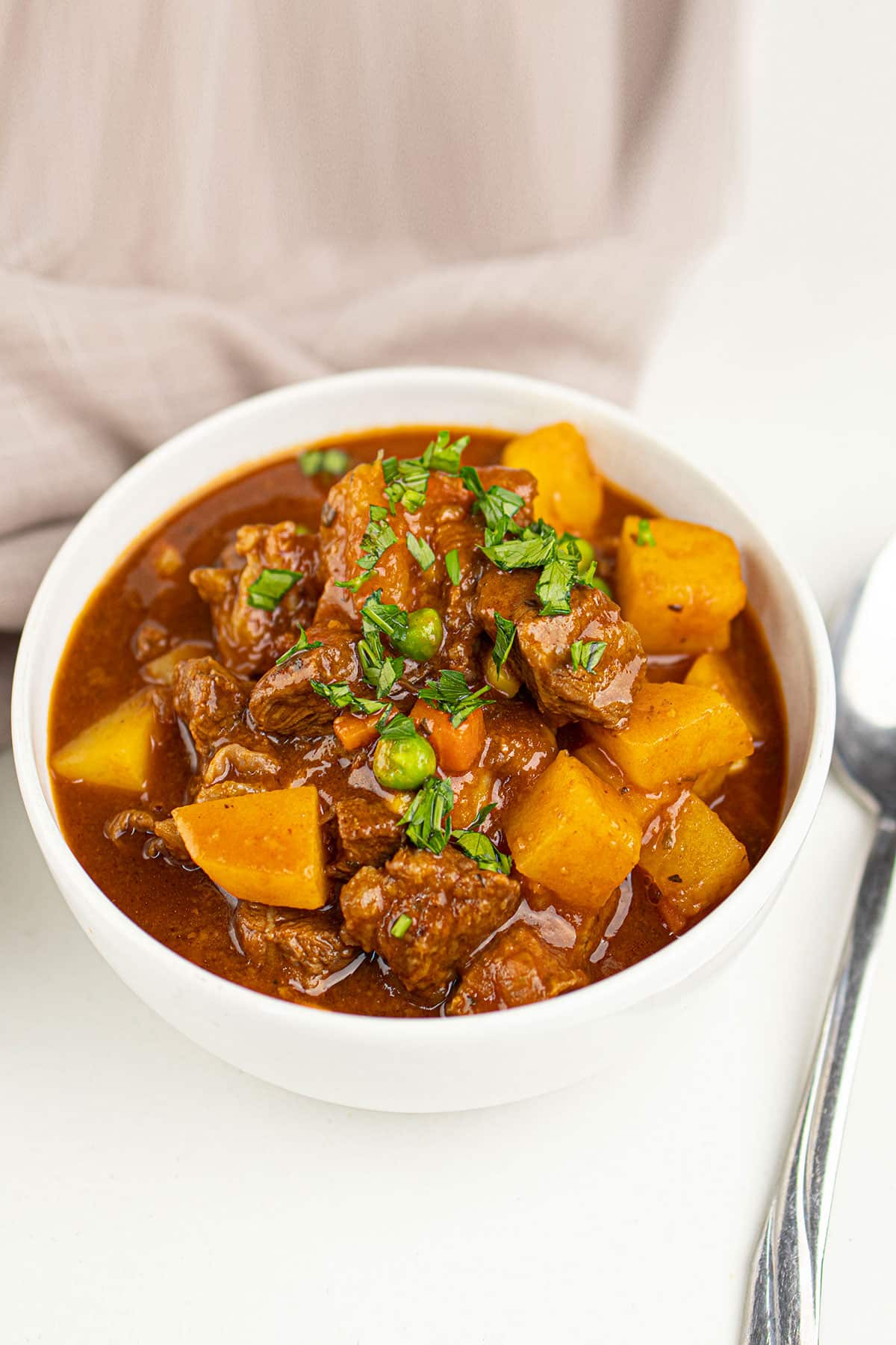 White bowl filled with easy slow cooker beef bourguignon on white background.