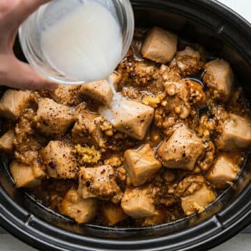 Cornstarch slurry being added to ingredients in crockpot.