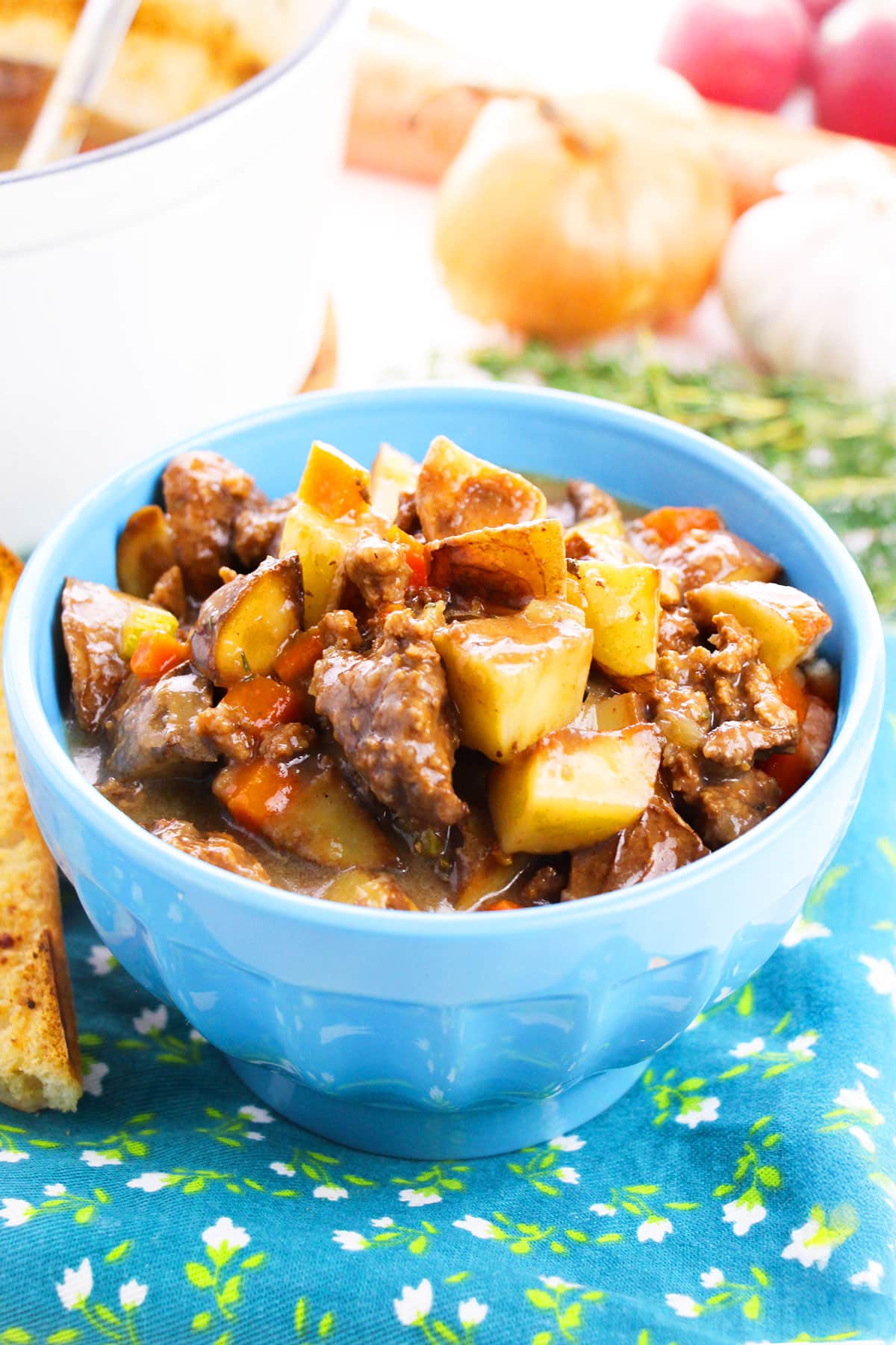 Easy slow cooker ground beef stew or poor man's stew served in blue bowl with blue pattern napkin underneath. 