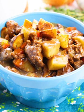 Easy slow cooker ground beef stew or poor man's stew served in blue bowl.
