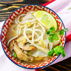 Easy slow cooker Vietnamese vegetarian pho served in patterned bowl on rustic wood background.