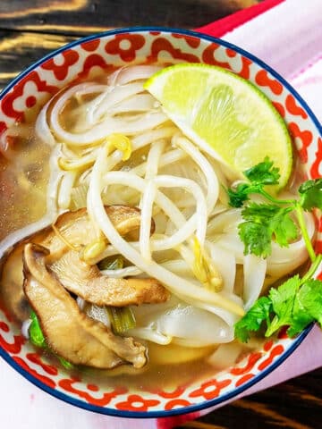 Easy slow cooker Vietnamese vegetarian pho served in patterned bowl on rustic wood background.