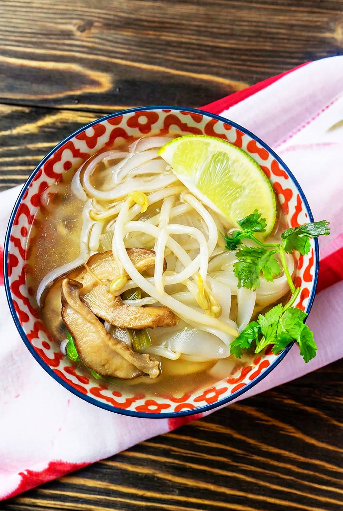 Easy slow cooker vegetarian pho served in patterned bowl on rustic wood background. 