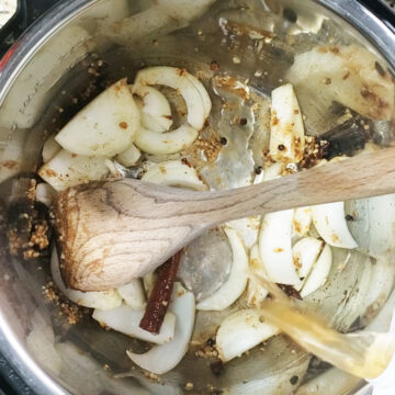 Spices, onions, ginger and garlic being sauteed in a pot. 